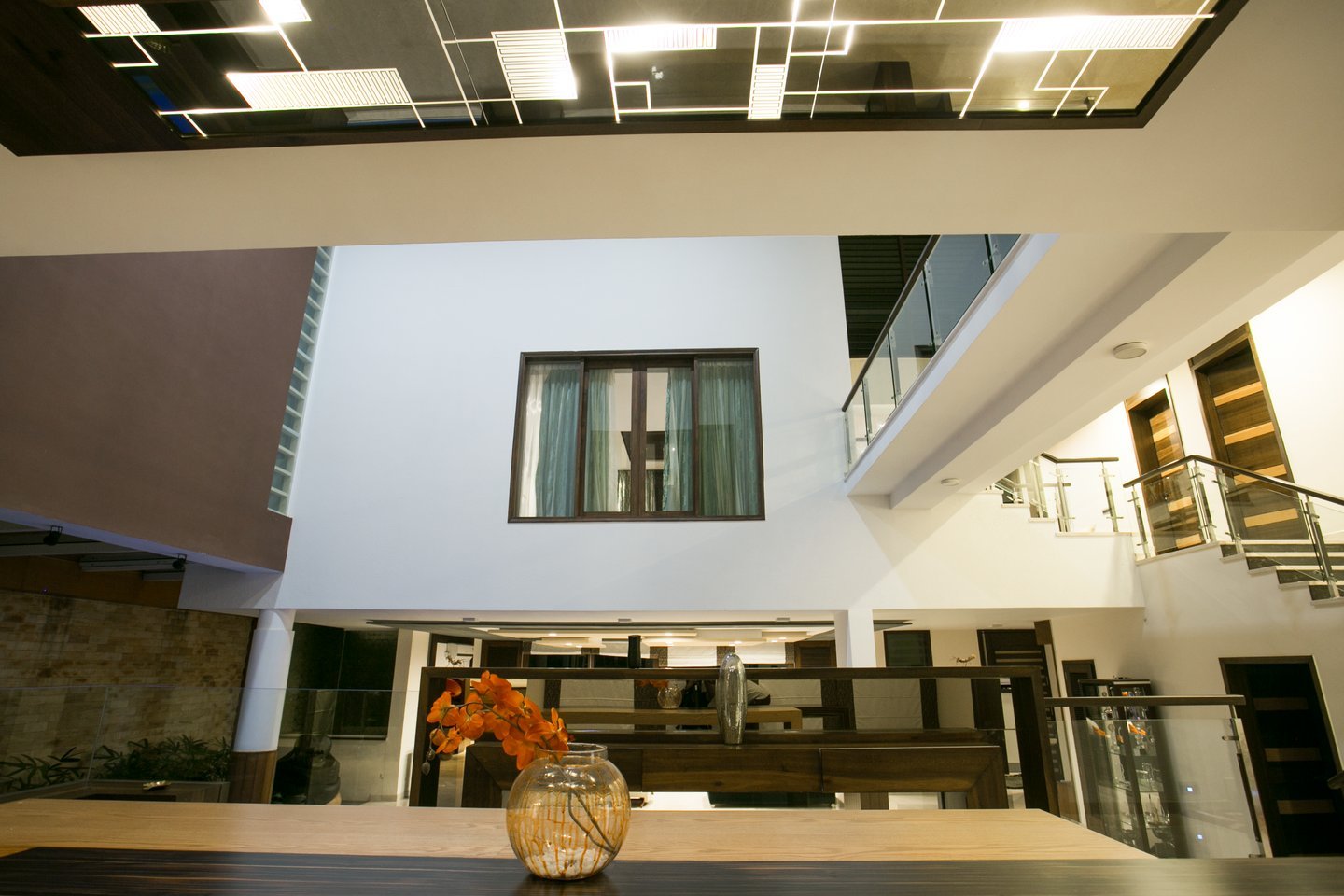 Atrium view past the dining table and flowers, up to the mirrored ceiling panel, upper gallery and staircase