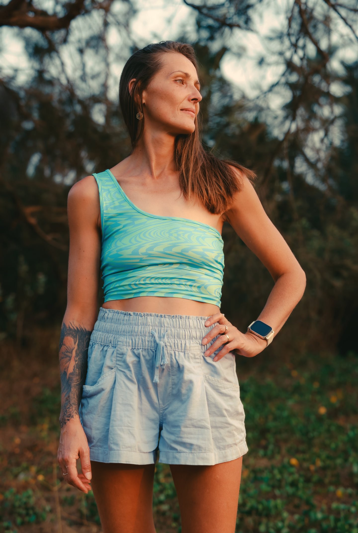 The model in a turquoise one-shoulder top, looking to the side in warm evening light